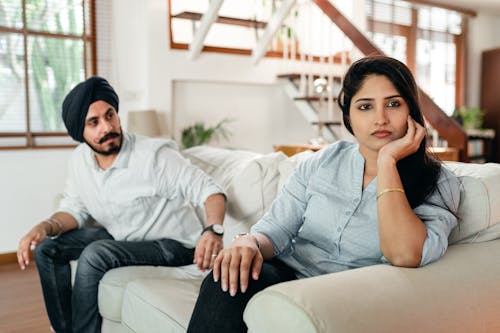 Young ethnic couple sitting on sofa after conflict