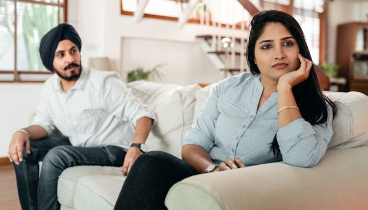 Serious Couple In Conflict Sitting On Couch In Living Room