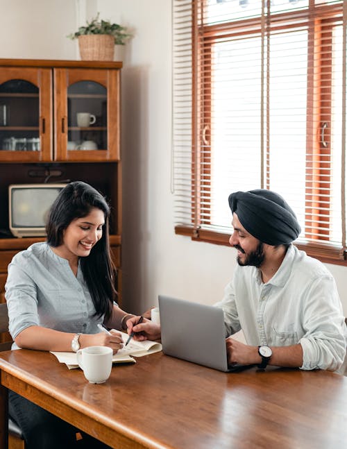 Happy Indian students doing homework together on kitchen using netbook