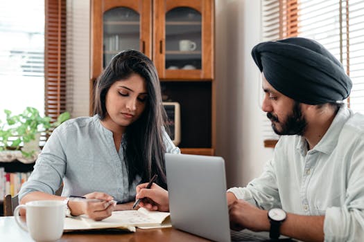 Two young professionals working together at home with a laptop.