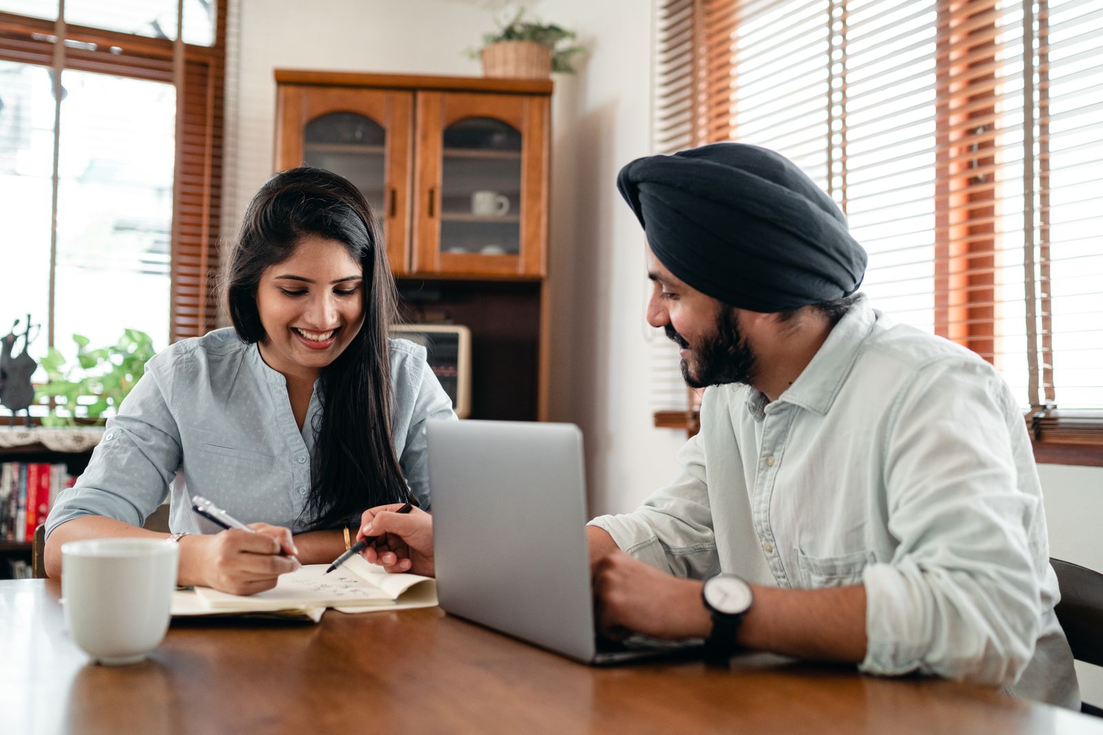 Indian coworkers discussing project details together beside a laptop in an office