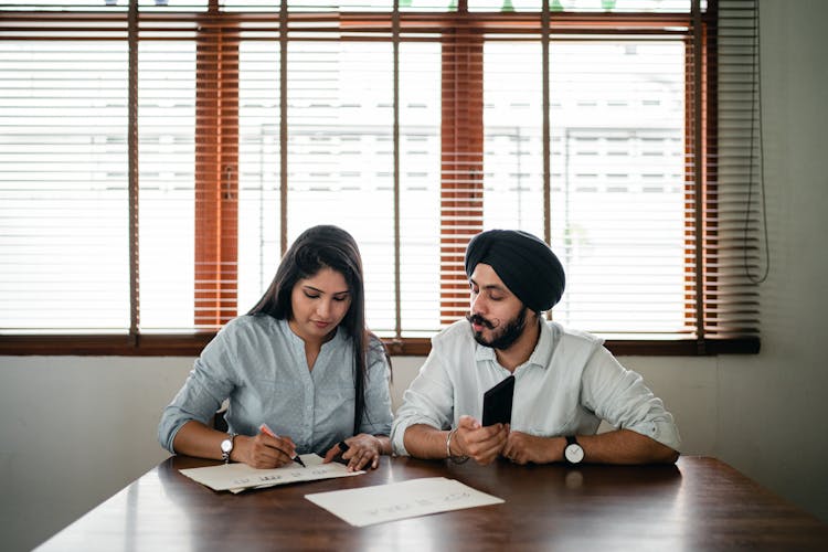 Indian Woman And Man Writing Posters At Table In Light Office