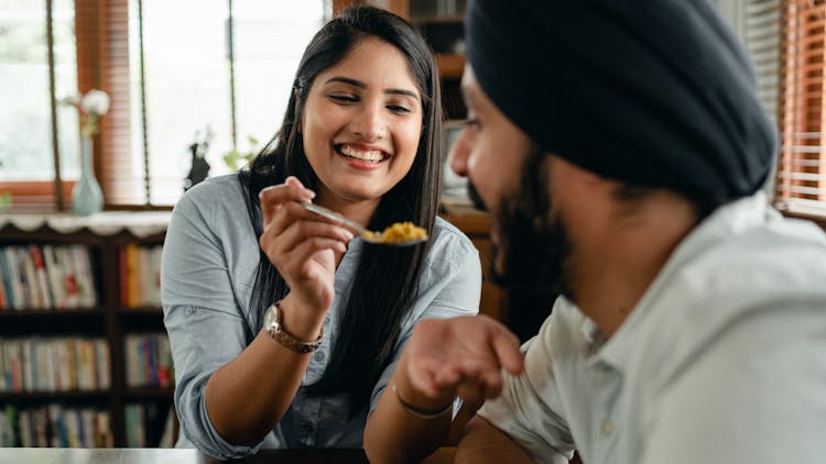 Positive Young Indian Couple Eating Traditional Dish Together During Lunch