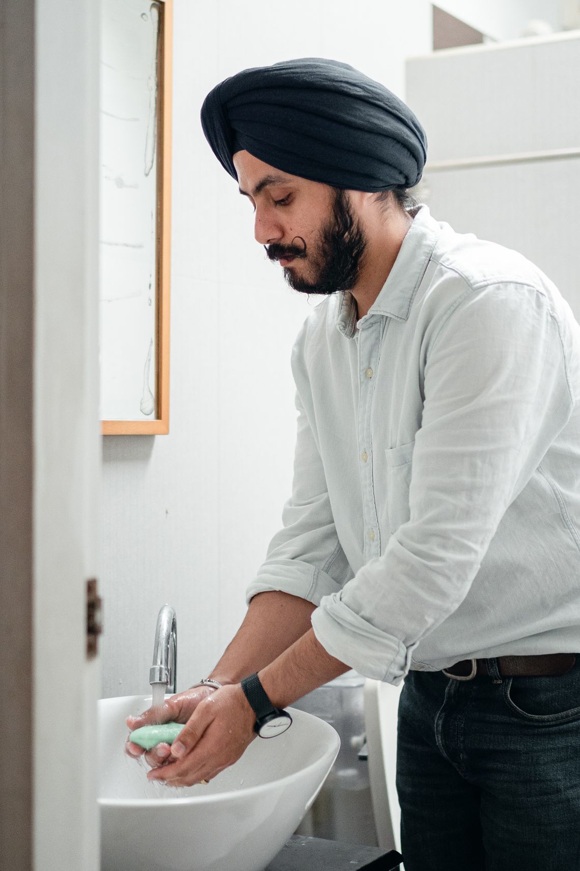 Man washing his hands with soap in a bright modern bathroom
