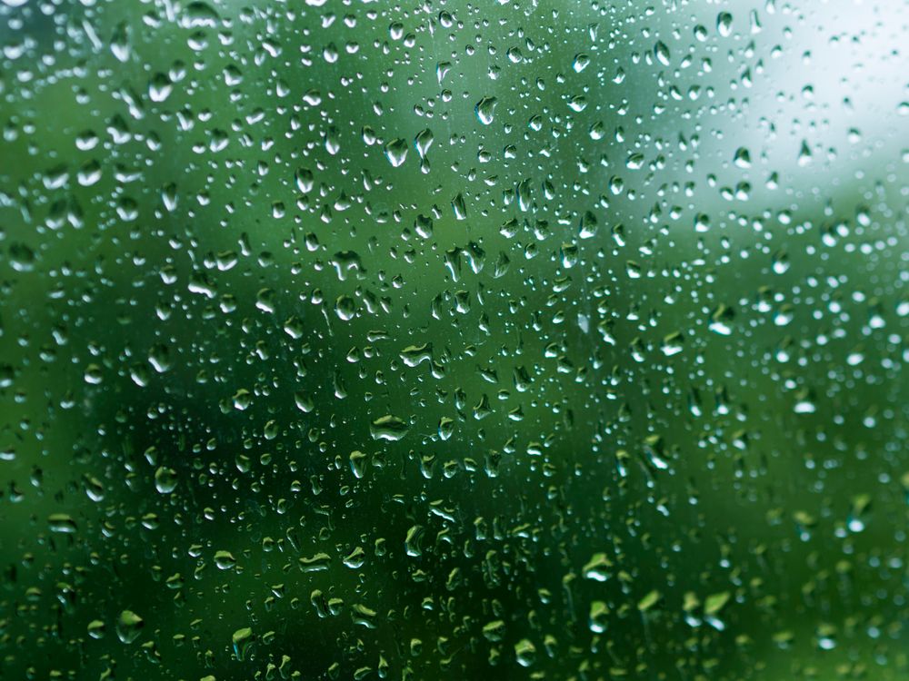 Free Close-up view of rain droplets on glass against a vibrant green background, evoking a fresh and calming atmosphere. Stock Photo