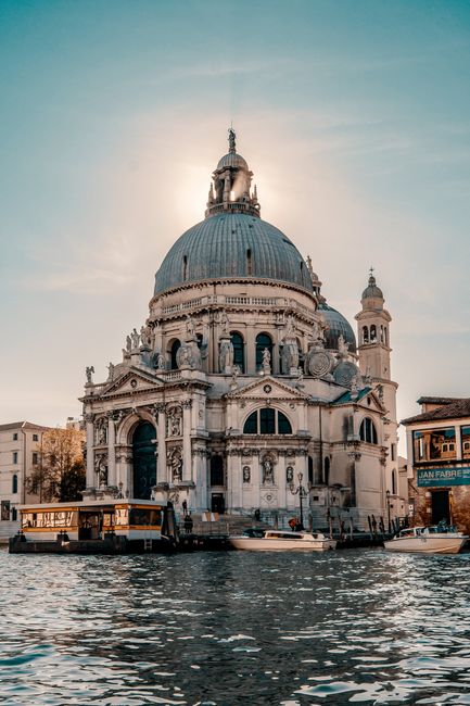 From below of old masonry Baroque style catholic cathedral near rippled canal under sky in evening in Italy