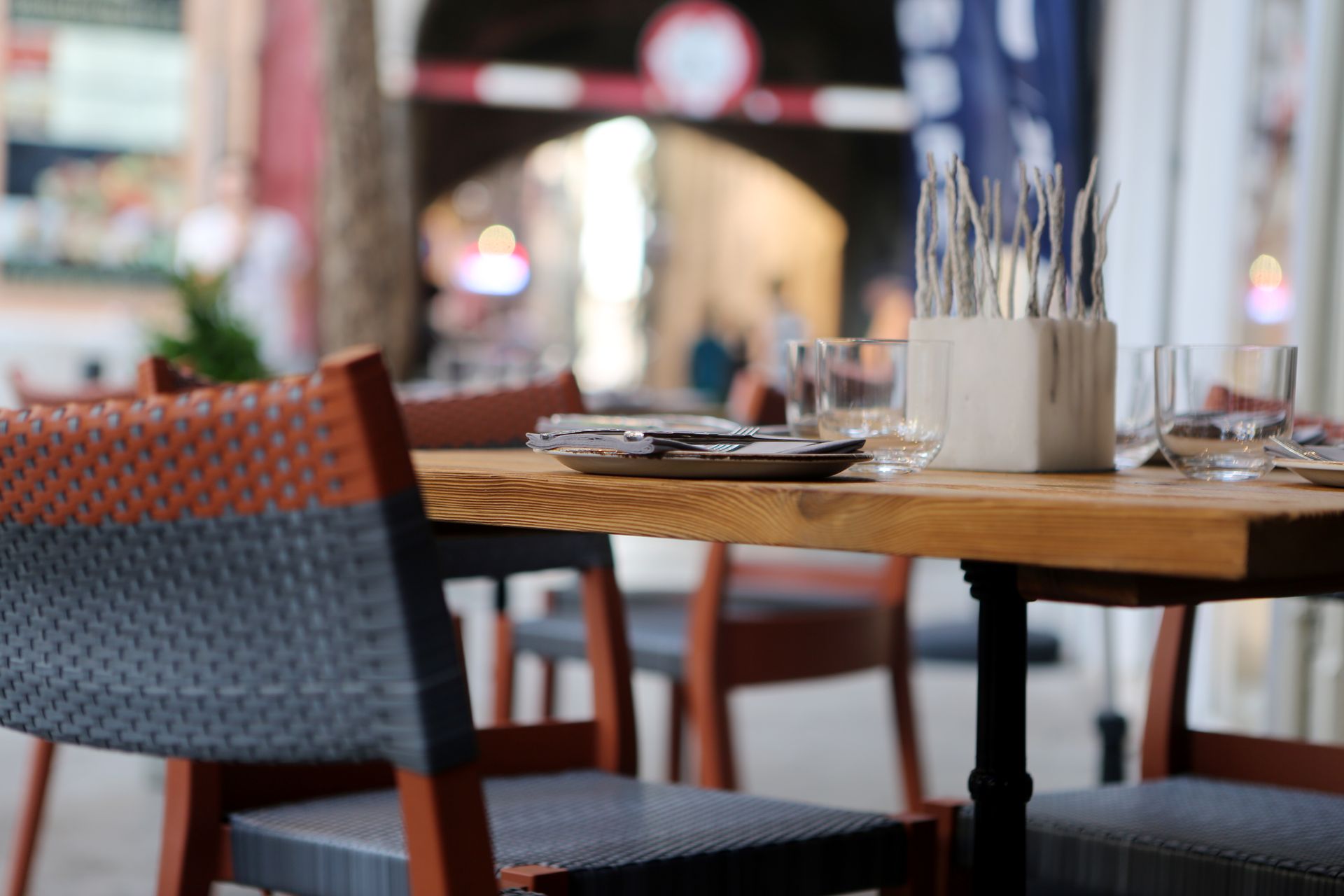 Cozy outdoor cafe with neatly set tables and chairs in a bustling urban alleyway.