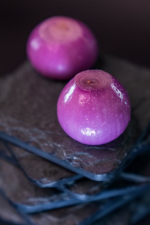 From above peeled red onions for food preparation placed on stack of boards in dark kitchen