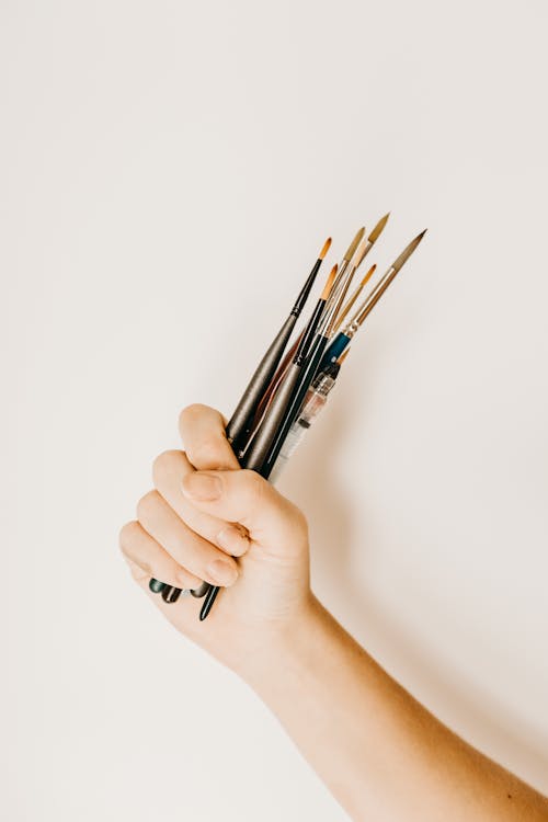 Free Crop person carrying set of paintbrushes Stock Photo