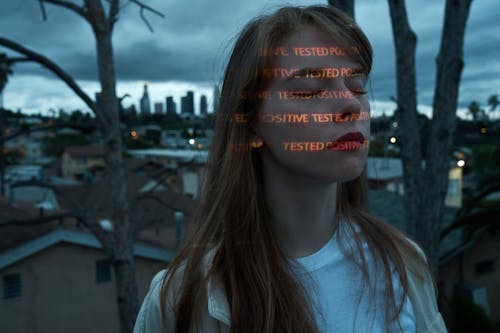 Calm woman with Positive Tested words on face on roof against cityscape