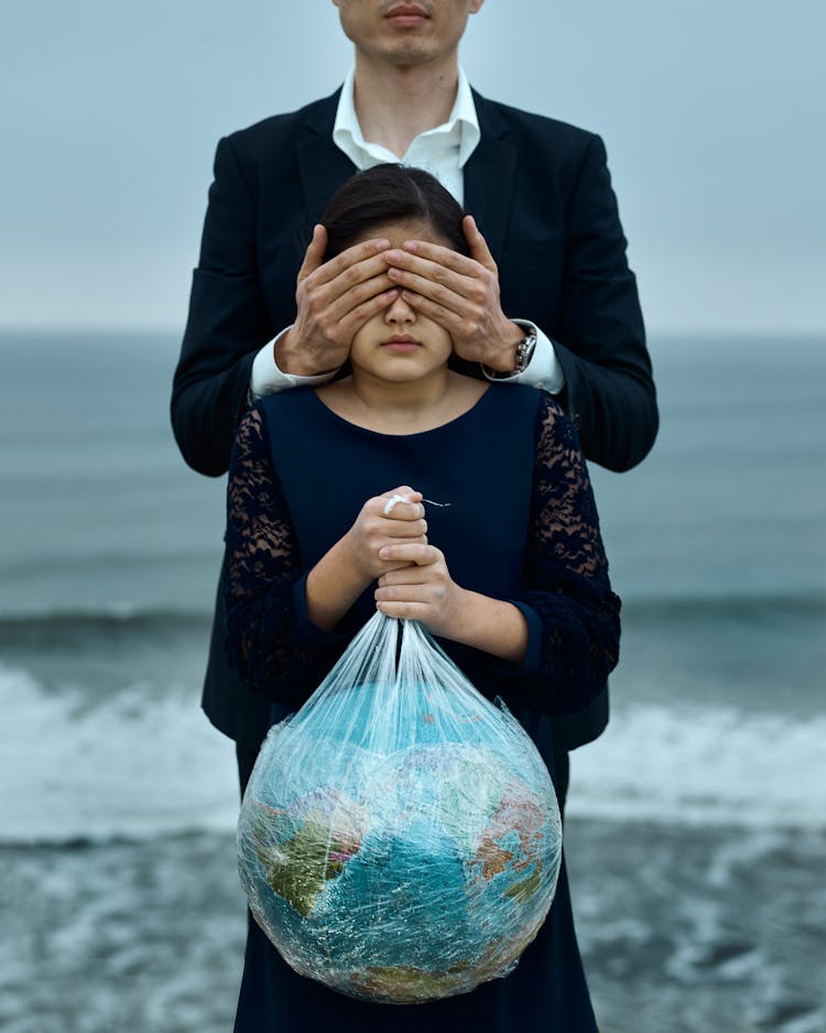 Man And Girl With Globe In Hands And Covered Eyes