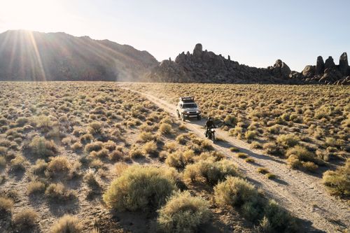 Free From above view of narrow road in dry highland valley with jeep and motorbike under bright evening sun Stock Photo