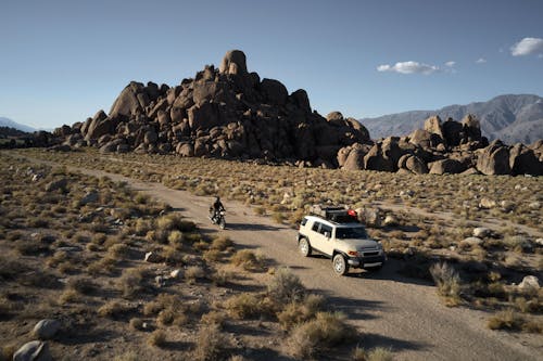 Car driving near motorbike in mountainous area in semidesert