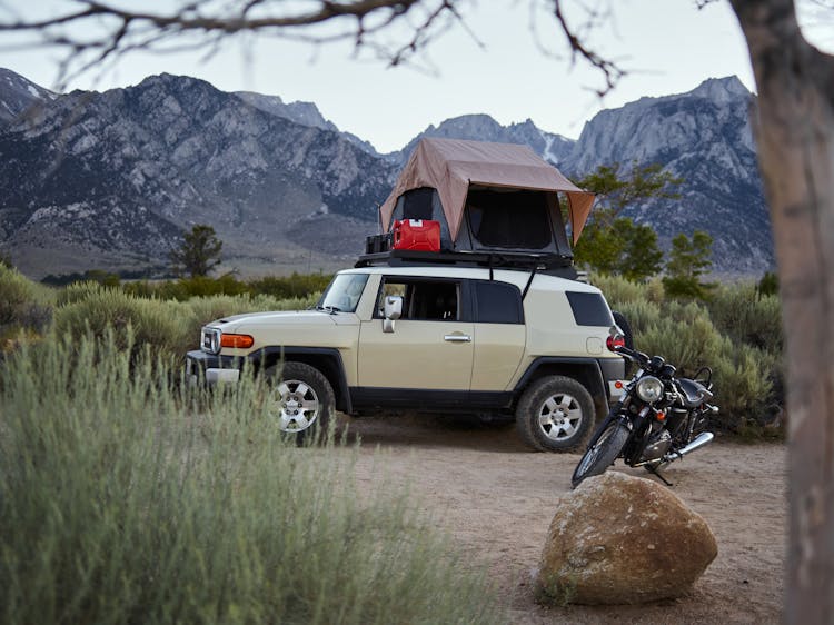 A Car With A Rooftop Tent Beside A Motorcycle