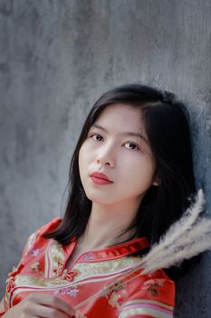 一位身着传统服装的年轻女子，在纹理灰色的墙壁前，肖像显得宁静