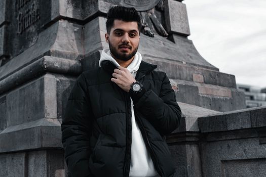 Stylish young man in warm jacket standing by a historic monument in Berlin, Germany.