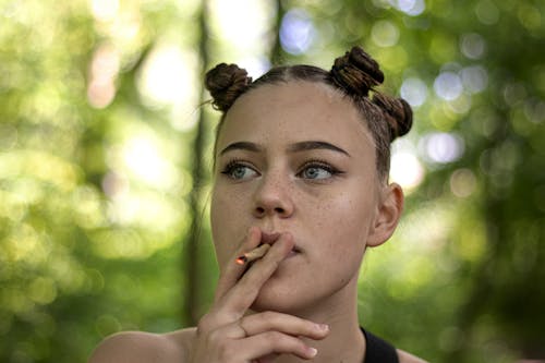 Free Young woman smoking cigarette in park Stock Photo