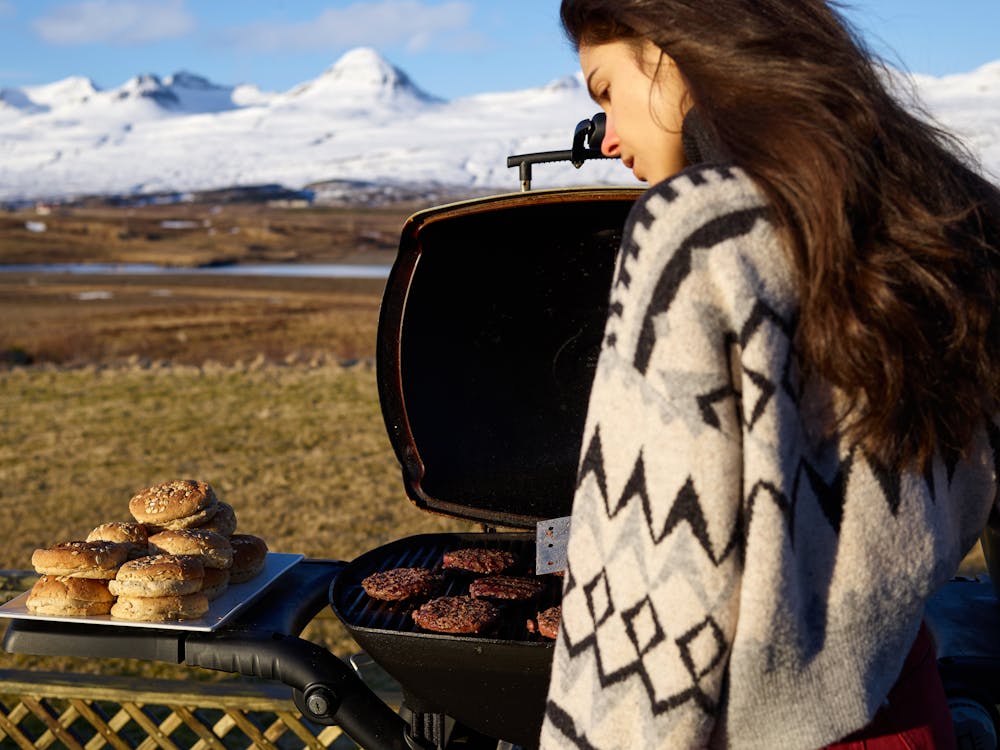 Young woman near portable BBQ in countryside