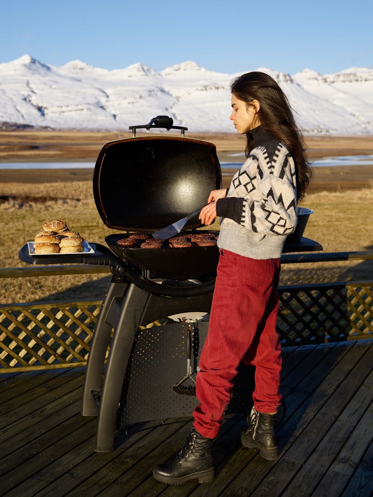 Concentrated Young Woman Grilling Steak During Winter Day