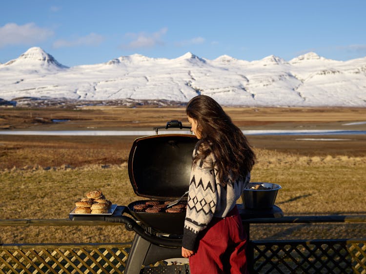 Woman Cooking Meat On Grill In Countryside