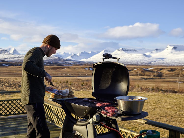 Young Man Grilling Meat In Camp