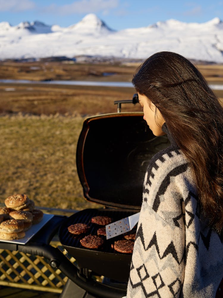 Young Woman Frying Meat On Grill In Countryside