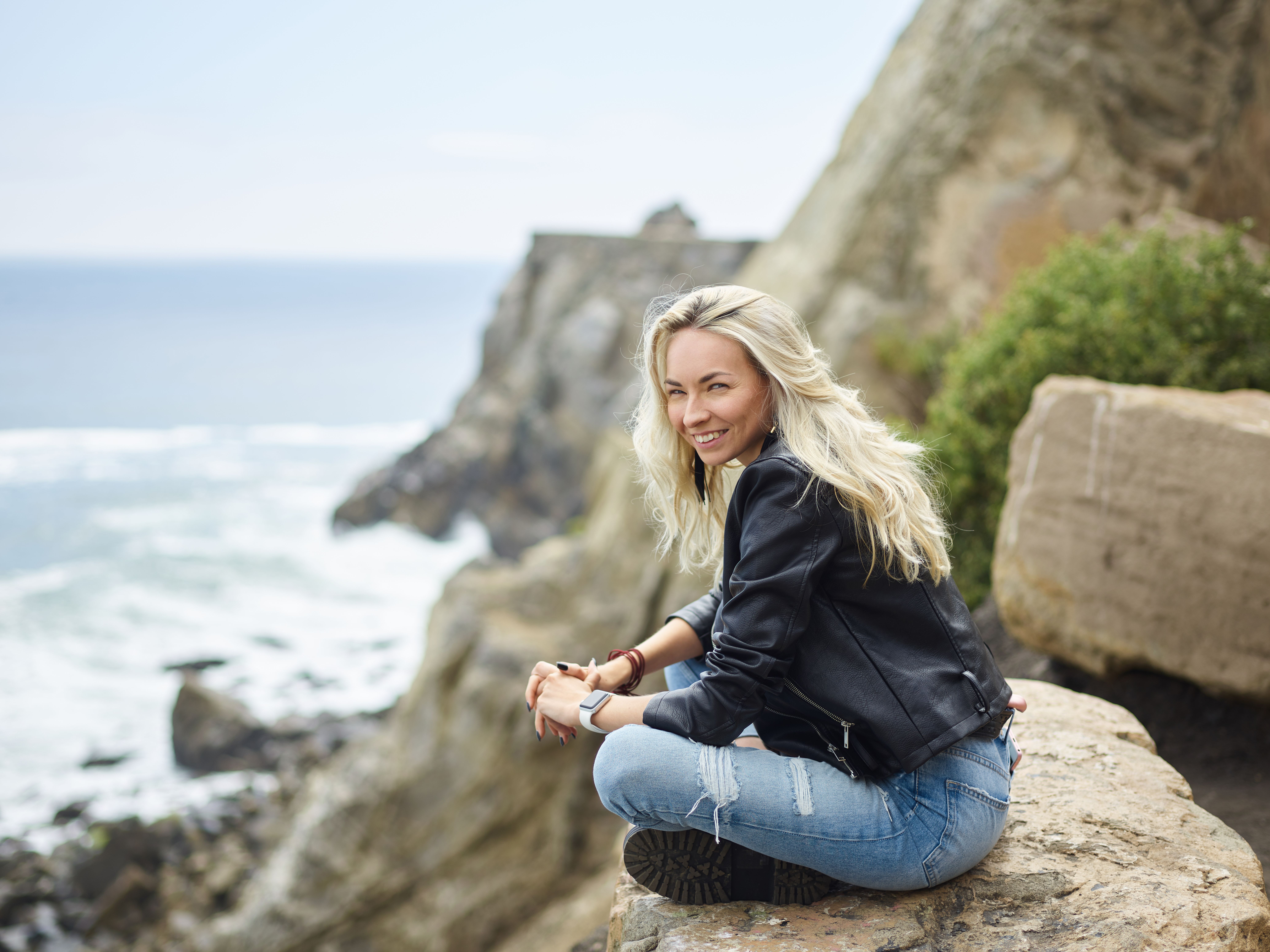 Young woman sitting on stone near seashore · Free Stock Photo
