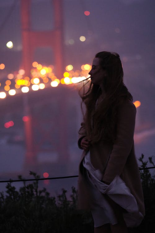 Melancholic young woman against illuminated city at night