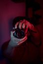 Unrecognizable male photographer with modern photo camera in red light in dark room