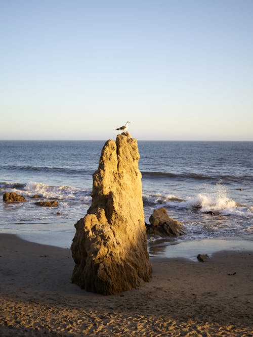 Huge rock on sandy ocean beach at sundown