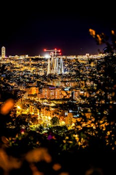 Stunning aerial view of Barcelona at night highlighting the illuminated Sagrada Familia amidst urban lights.