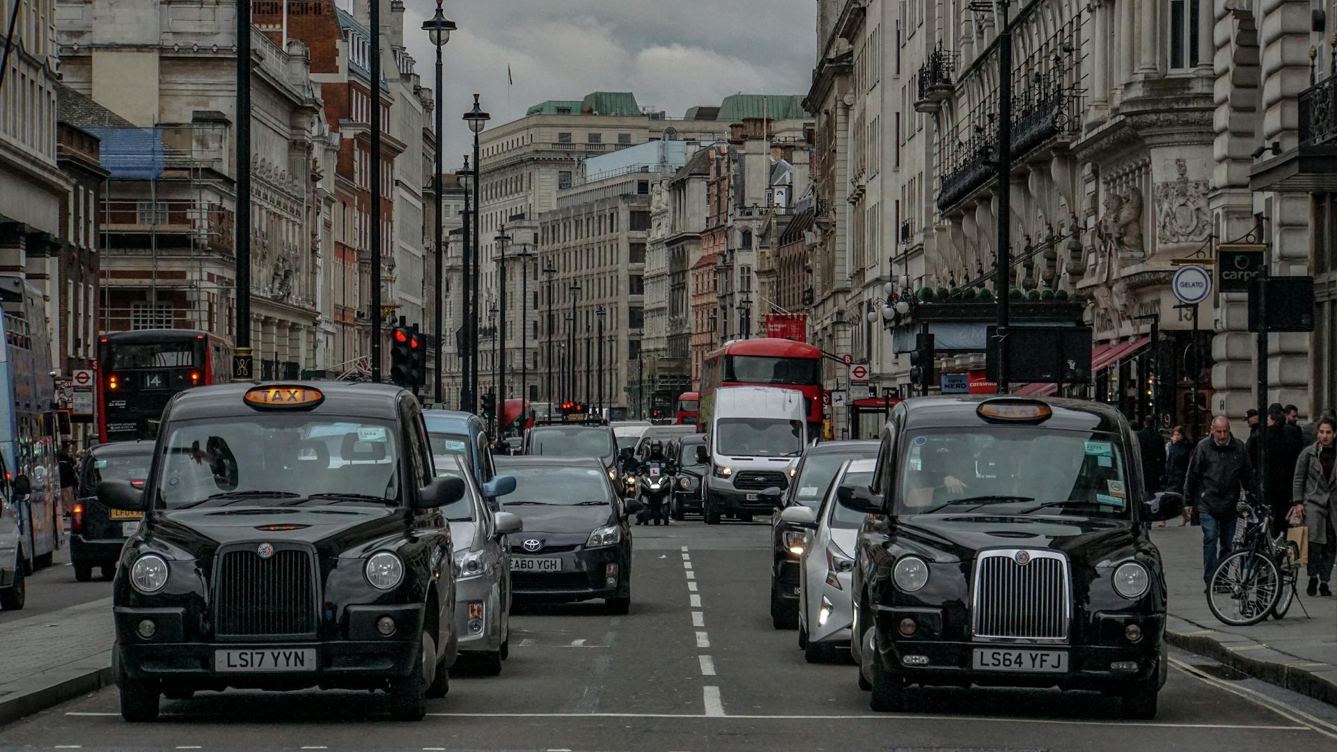 Crowded street scene in London with iconic black cabs and historic buildings.