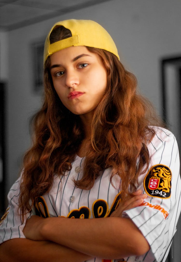 Woman With Red Hair Wearing A Baseball Shirt And A Yellow Cap