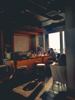 Warmly lit coffee shop interior with people enjoying their drinks by the window.