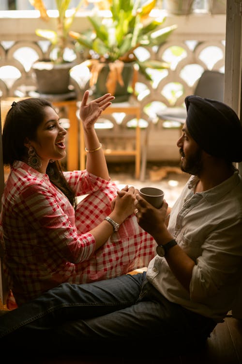 Young positive Indian couple discussing daily life and gesticulating