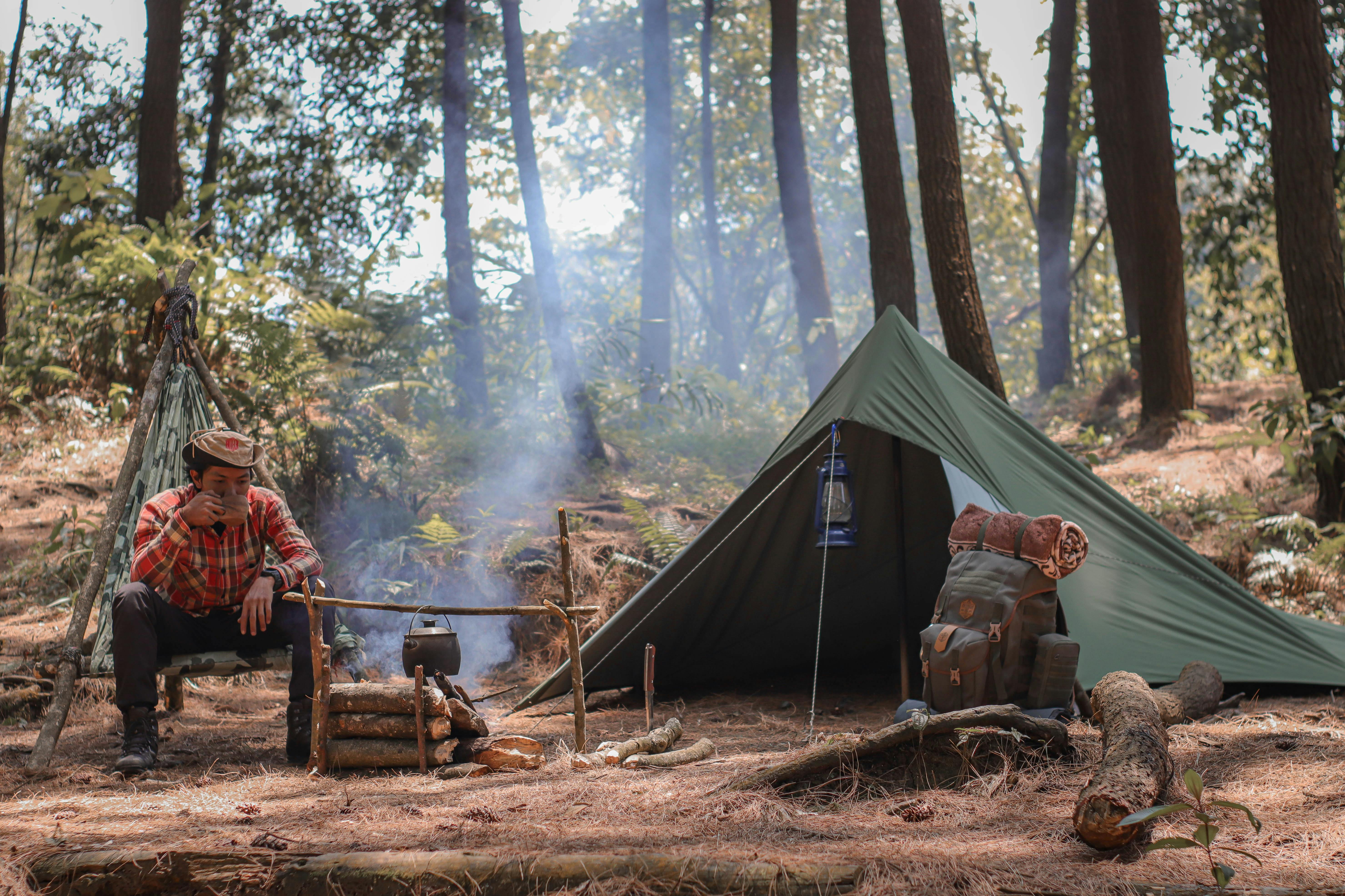 hiker resting near fire and tent during travelling