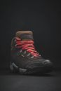 Male comfortable footwear with red lace for hiking placed on black background in studio