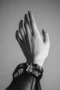 Black and white hand of crop anonymous young female wearing dark translucent clothes stretching up against wall
