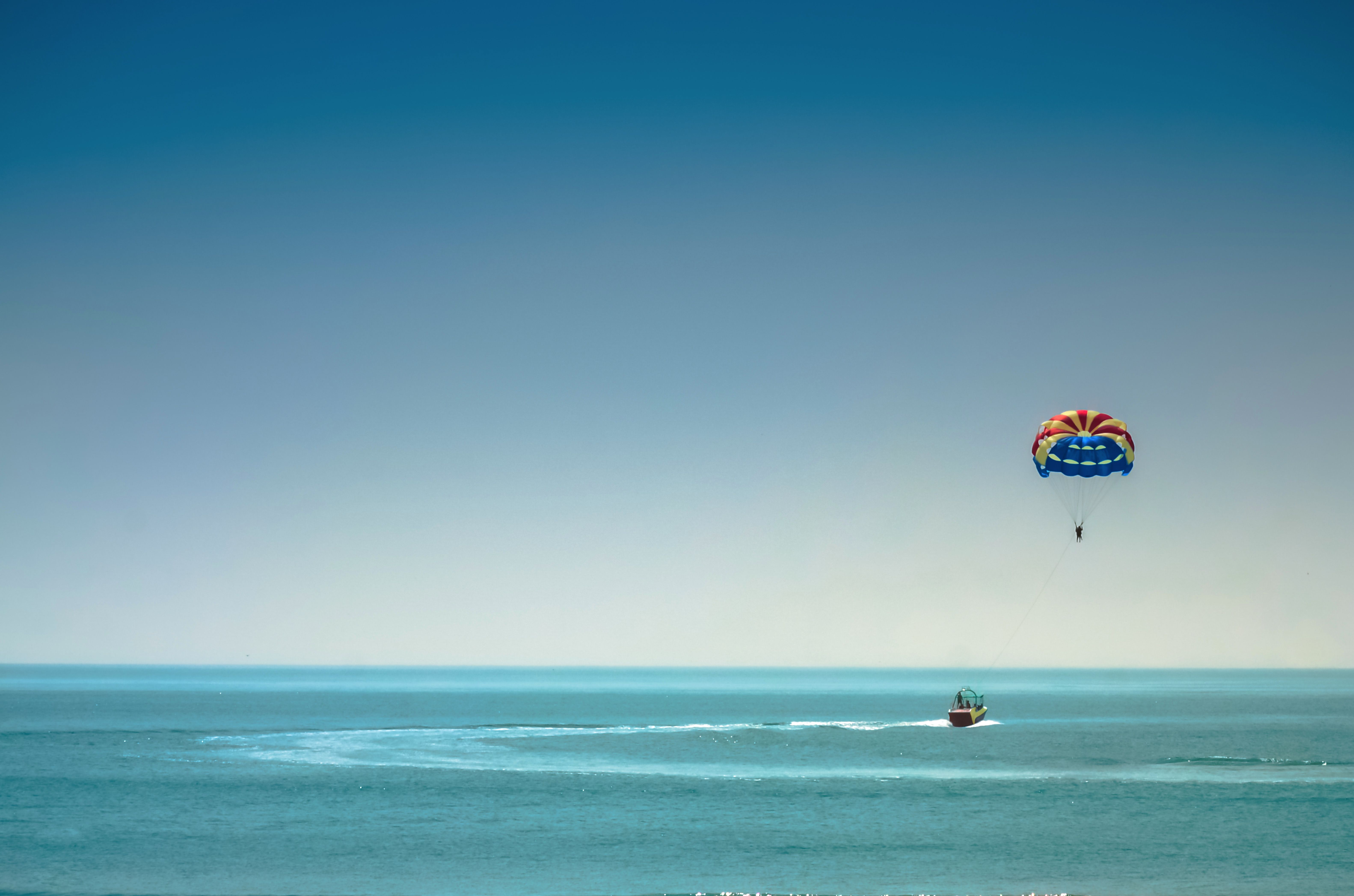 A vibrant parasailing experience over the vast blue ocean under a clear sky.