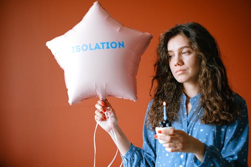 A Sad Woman Holding a Cupcake and a Star Shaped Balloon