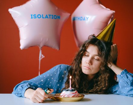A woman with party hat and cupcakes during an isolation birthday.