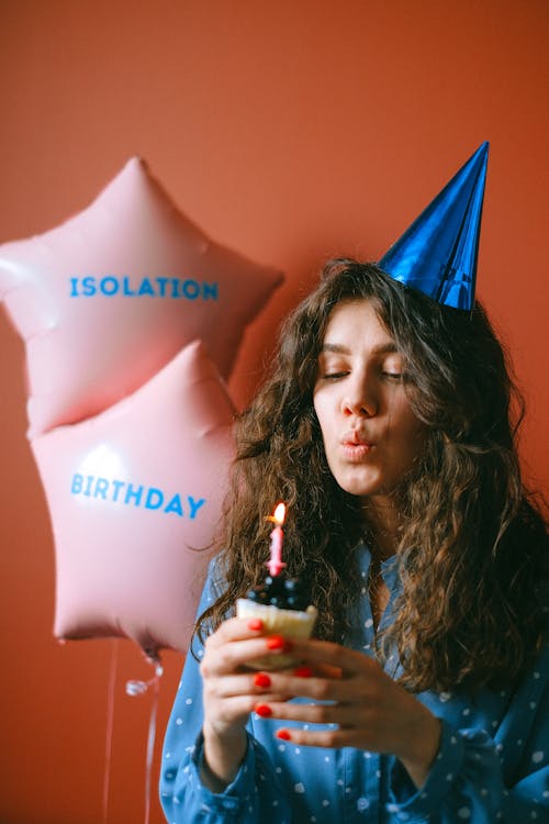 A Woman Blowing the Candle on the Birthday Cupcake She is Holding