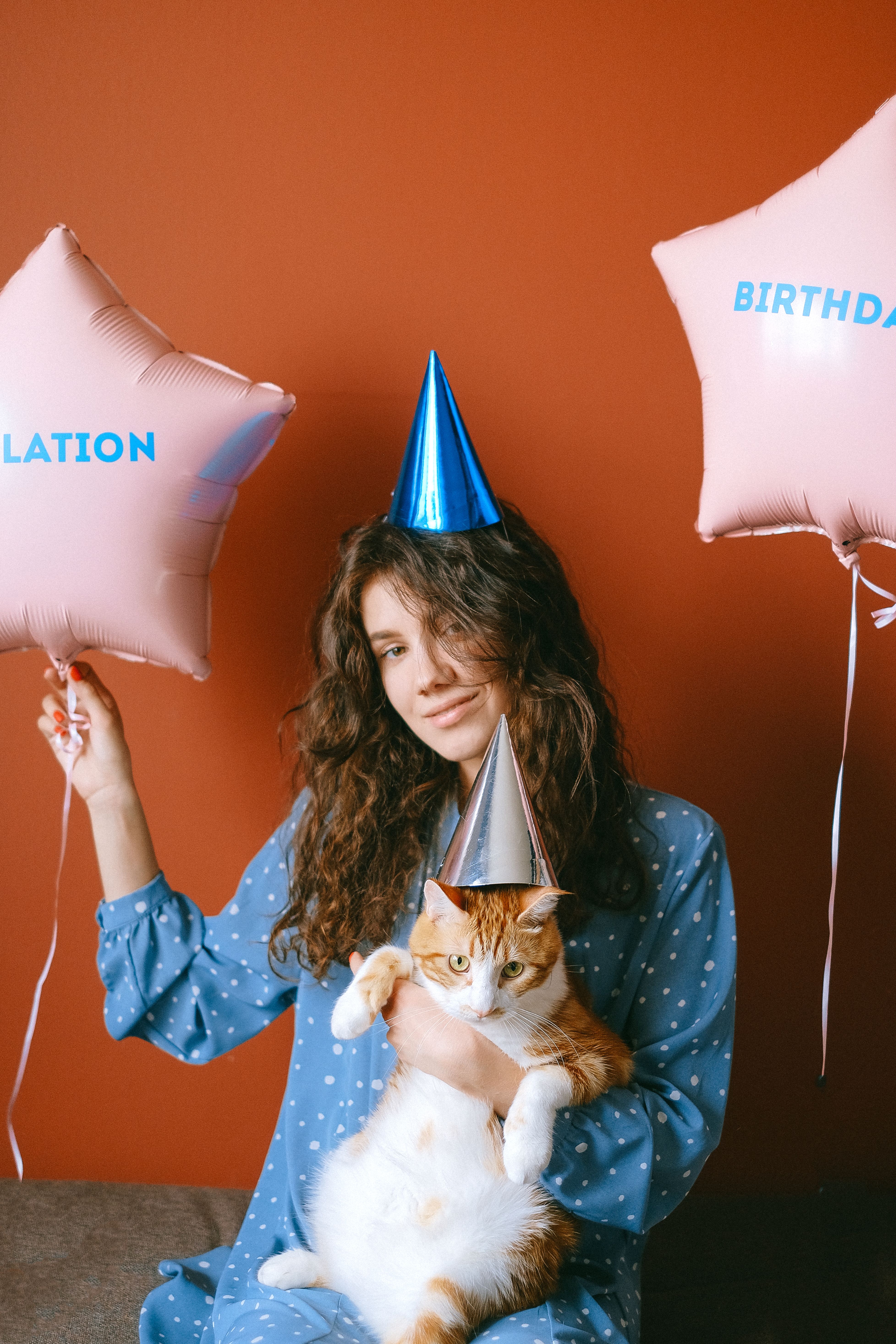 一位戴着气球派对帽、抱着猫的女性，非常适合生日庆祝活动