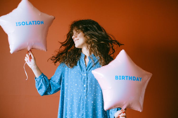 A Woman Flipping Her Hair While Holding Star Shaped Balloons