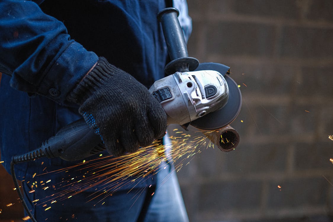A Person Cutting a Metal Using a Grinder