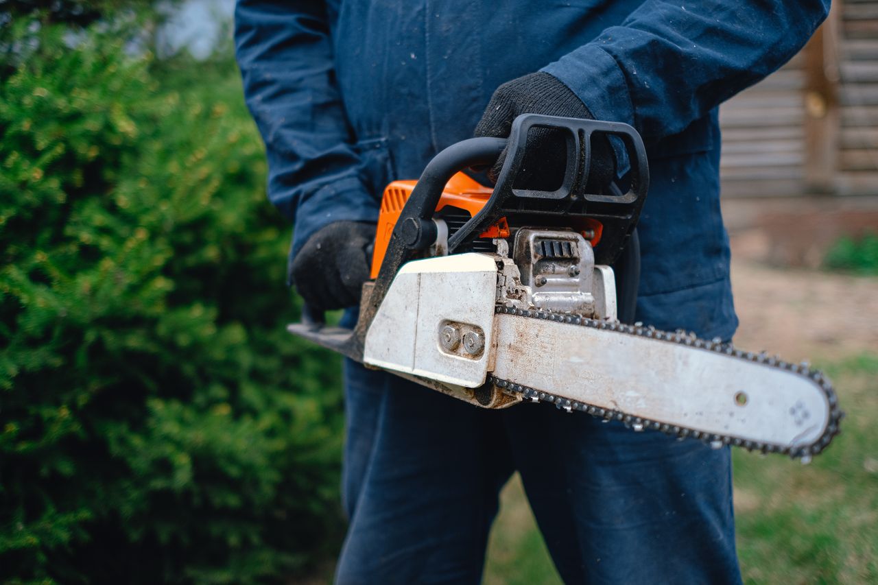 close up of a worker holding a chainsaw ideal for carpentry and outdoo