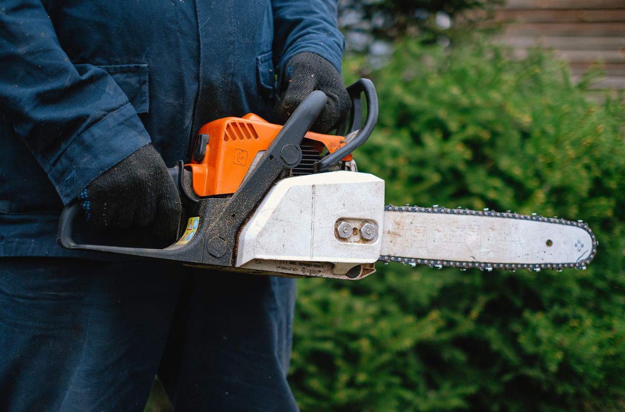 close up of a worker holding a chainsaw highlighting carpentry tools a
