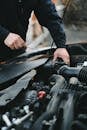 Person in Black Long Sleeves Repairing the Car Engine
