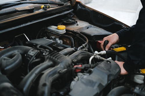 Person in Black Jacket Working on the Engine of the Car