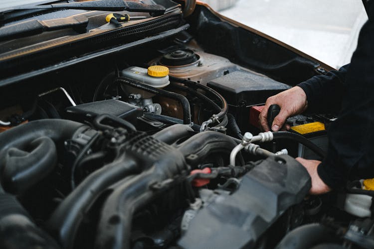 Person In Black Jacket Working On The Engine Of The Car